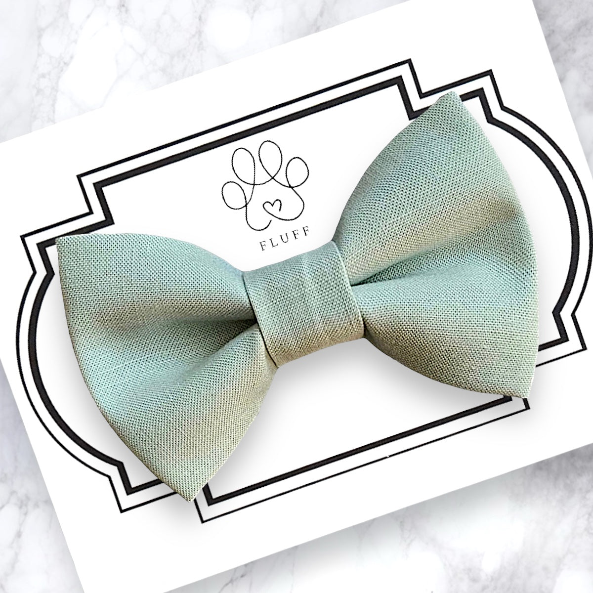 Light green dog bow tie on a white card with 'Fluff' branding