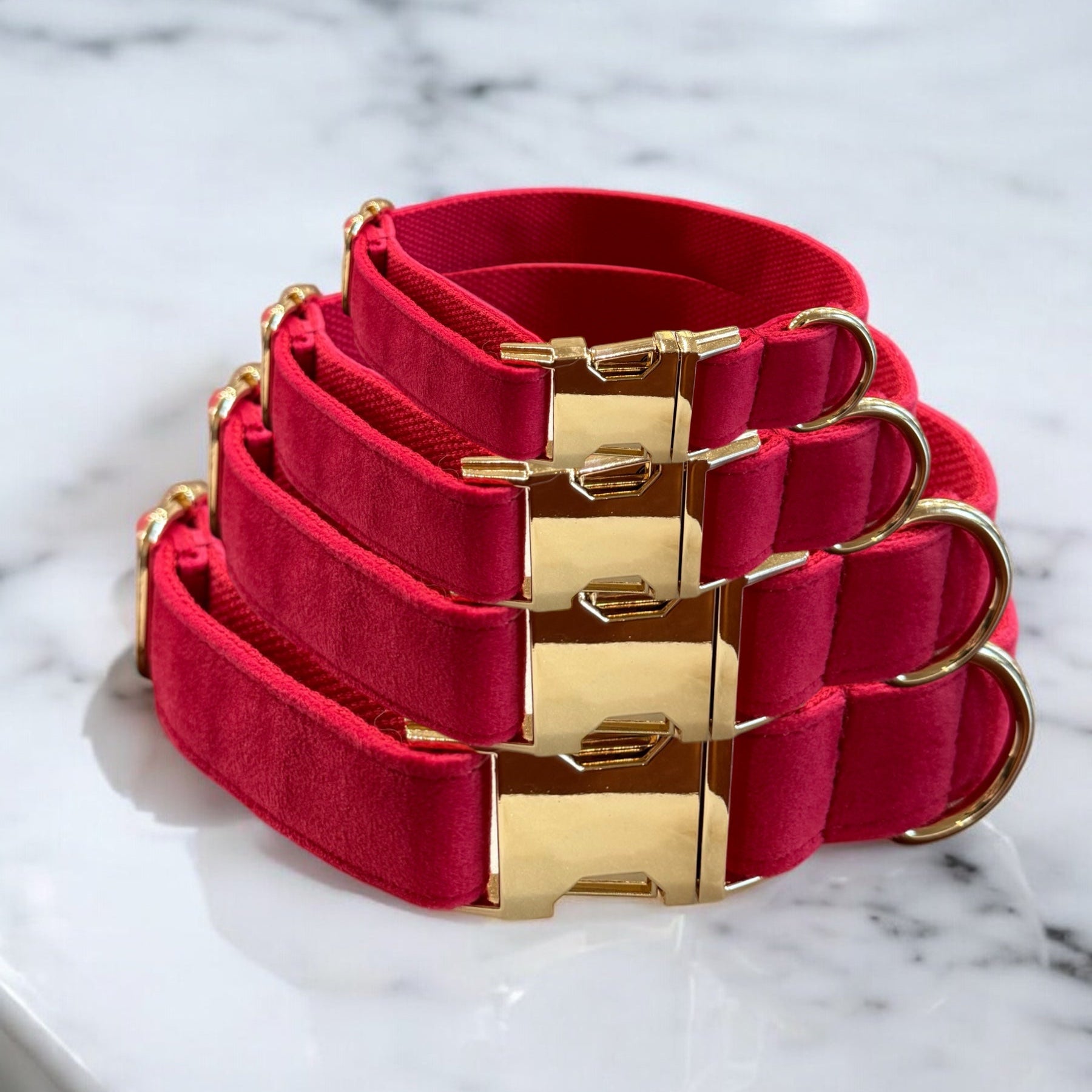 Set of pink dog collars with gold buckles on a marble surface