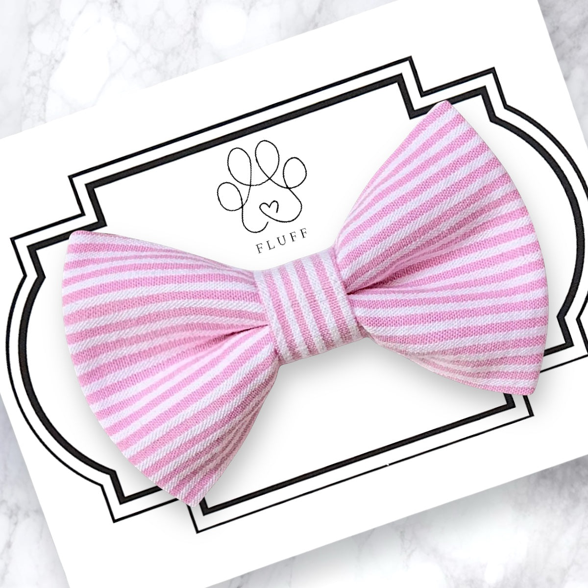 Pink and white striped bow on a white card with 'FLUFF' branding.
