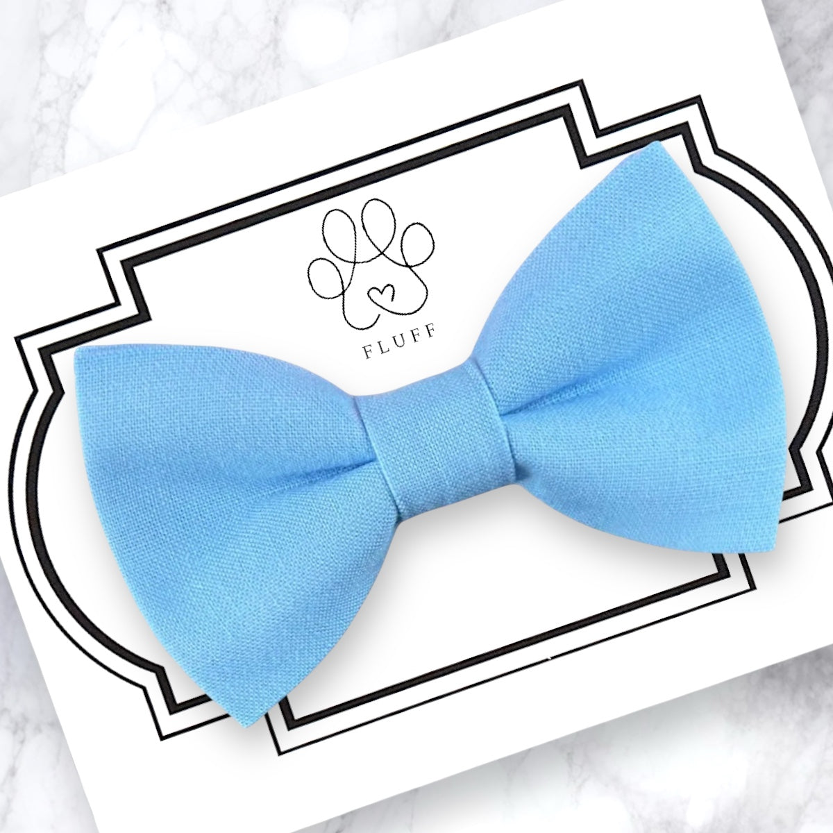 Light blue dog bow tie on a branded card with 'Fluff' logo.