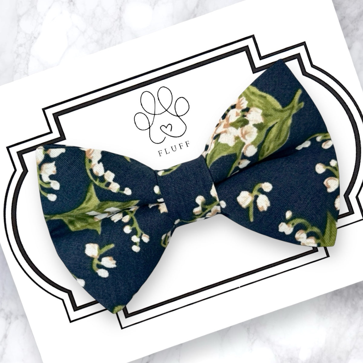 Navy blue bow tie with floral pattern on a white card with 'Fluff' branding.