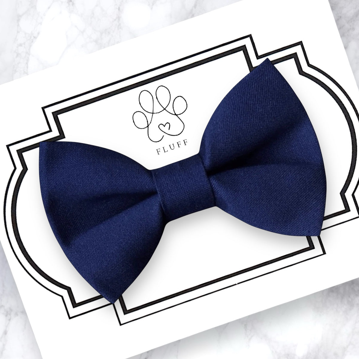 Navy blue dog bow tie on a white card with 'Fluff' branding