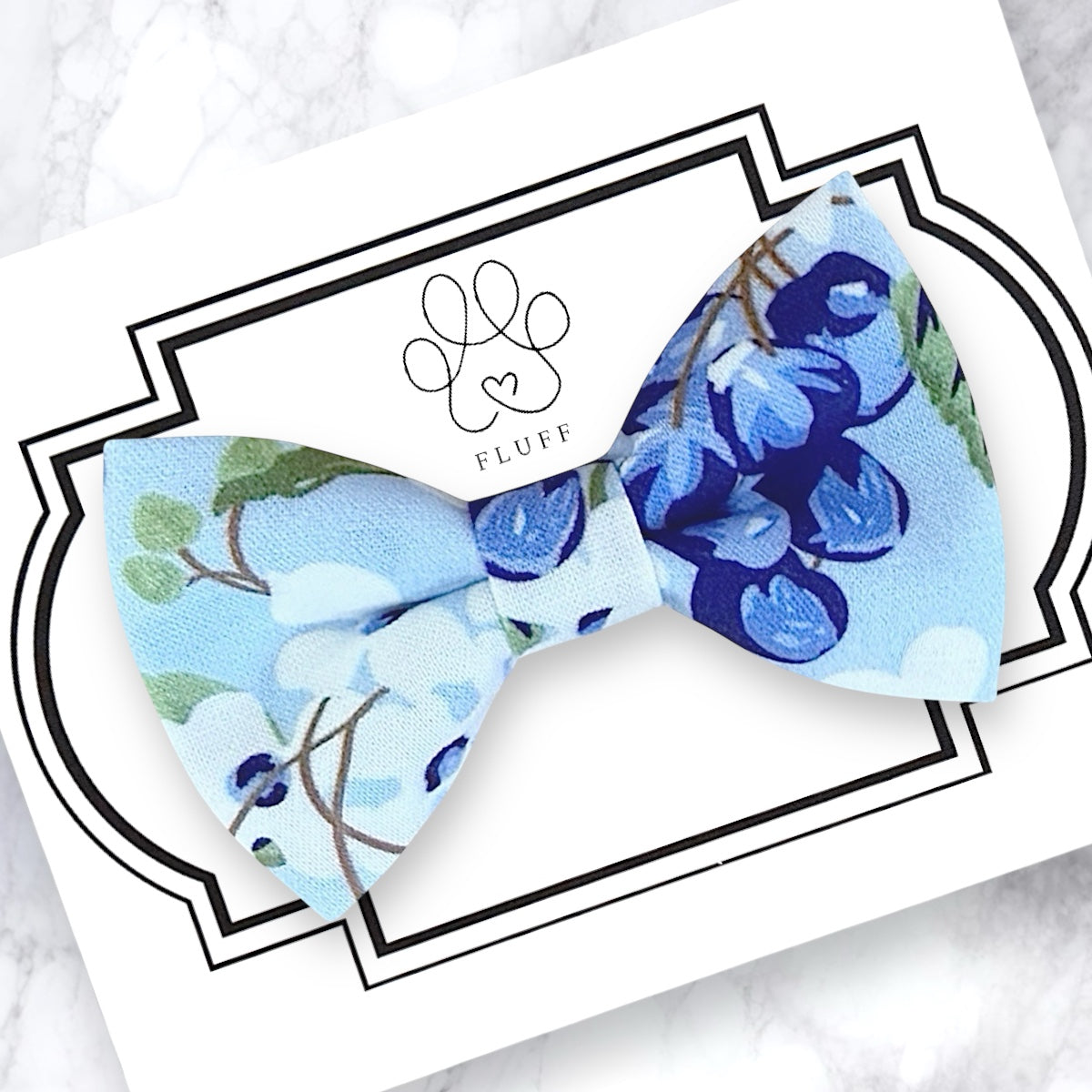 Floral blueberry dog bow tie on a branded card with 'FLUFF' logo.