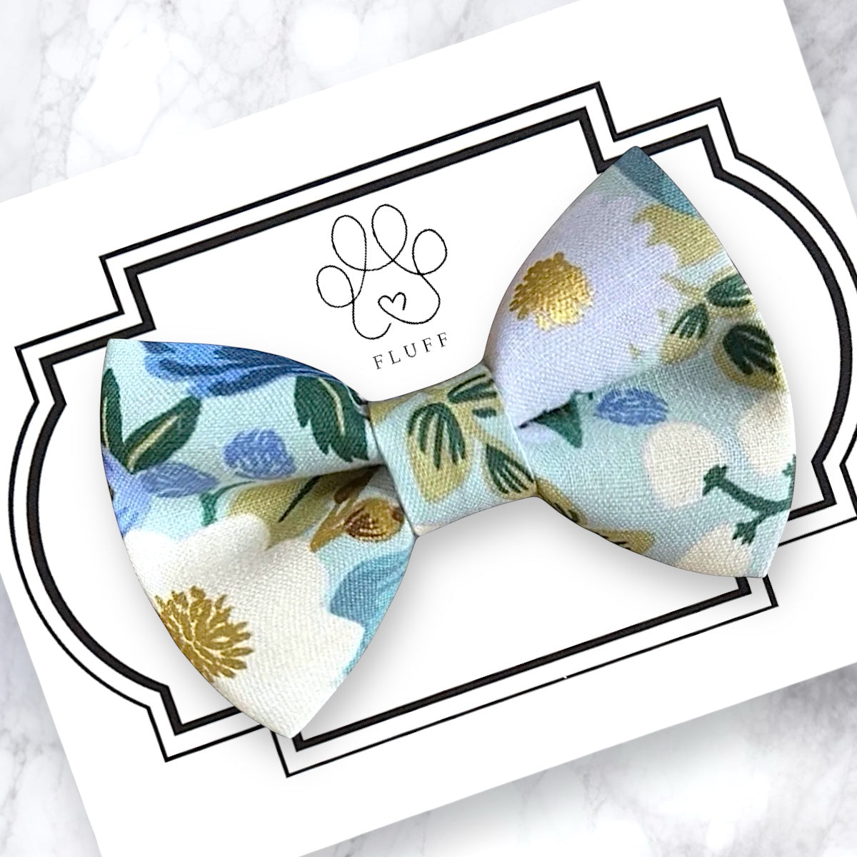 Floral patterned dog bow tie on a branded card with 'Fluff' logo.
