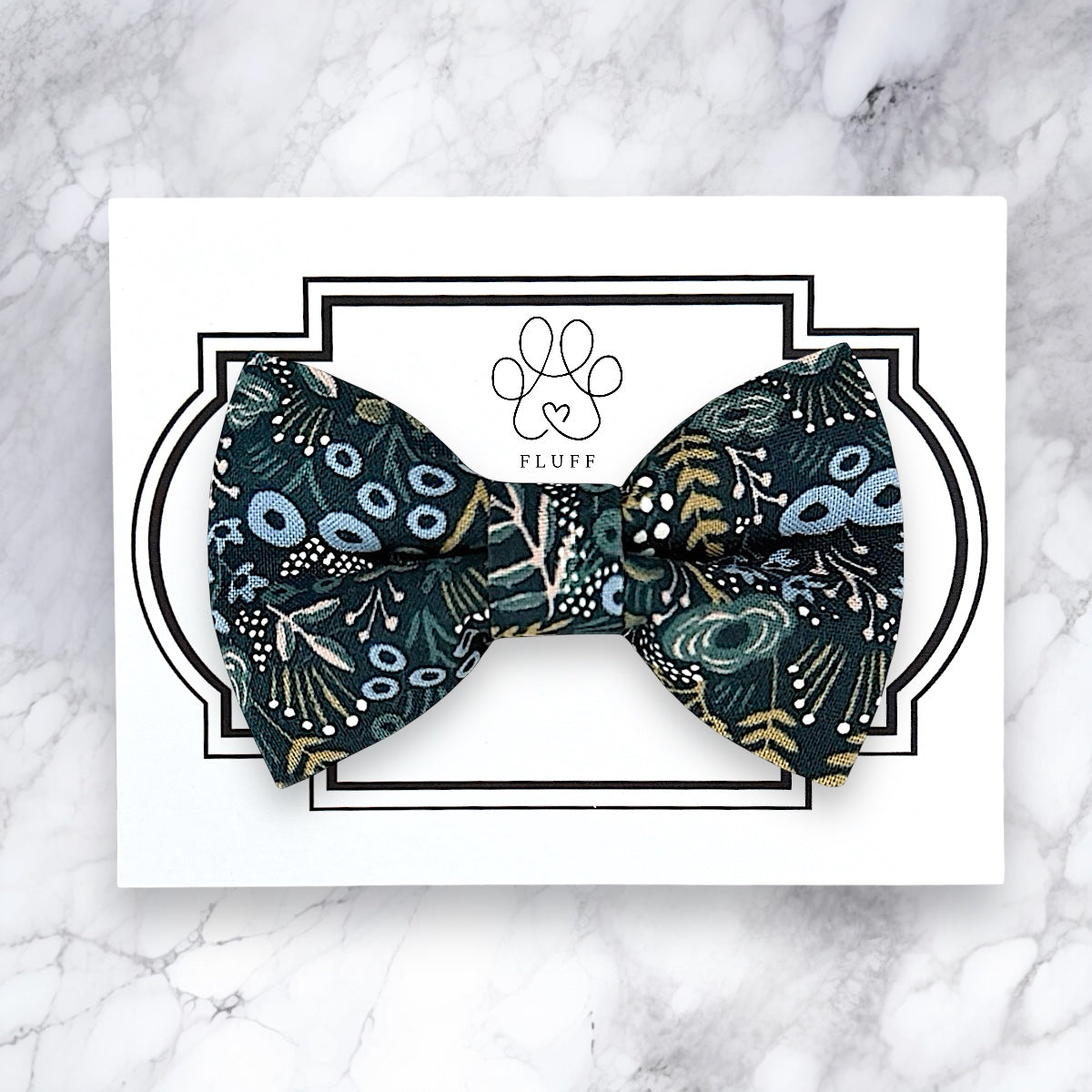 Patterned bow tie on a white card with 'FLUFF' branding on a marble background