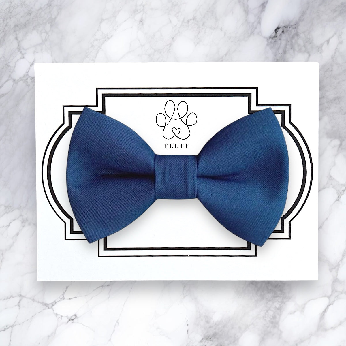 Steel blue bow tie on a white card with 'FLUFF' branding on a marble background