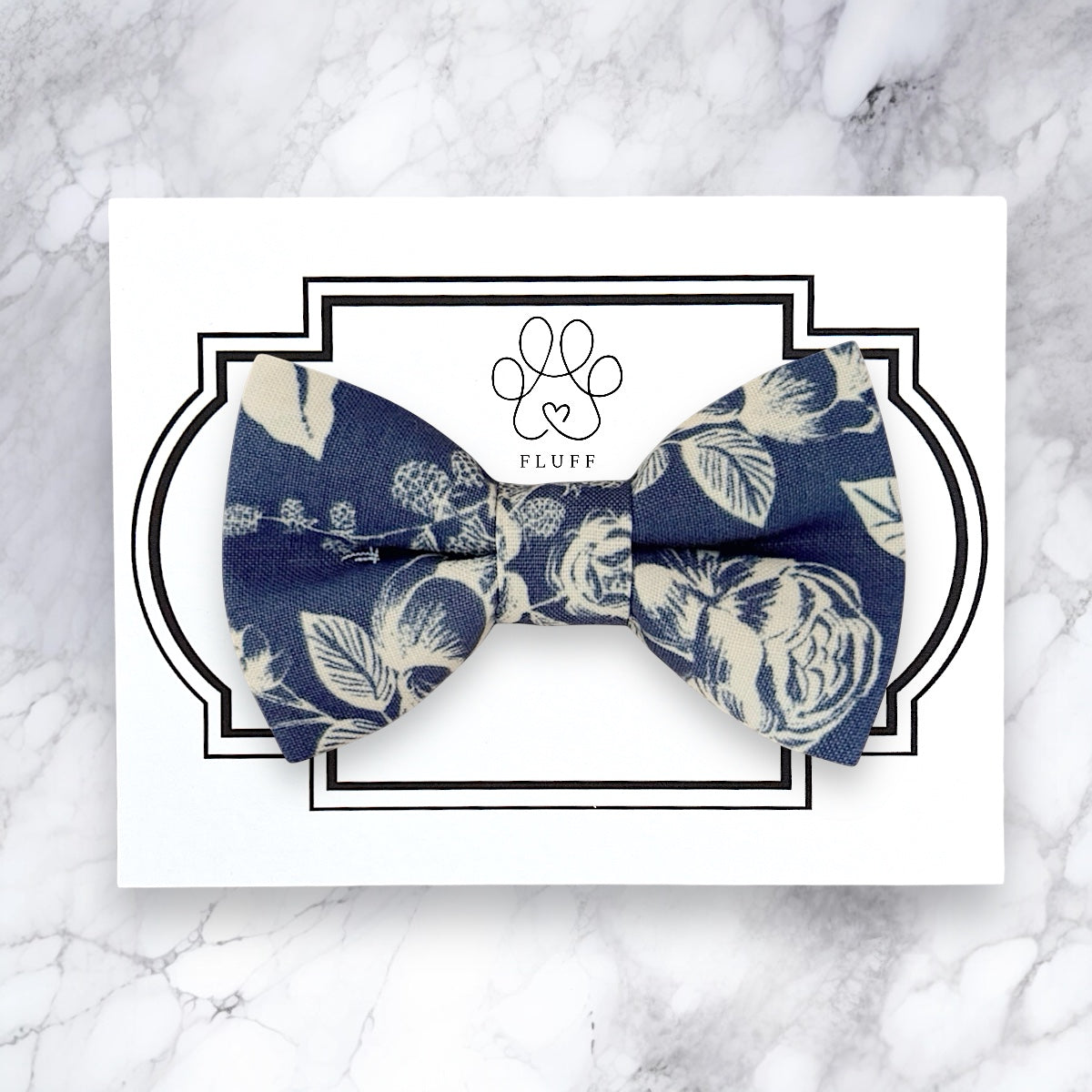 Steel blue floral bow tie on a marble background with 'Fluff' brand logo.