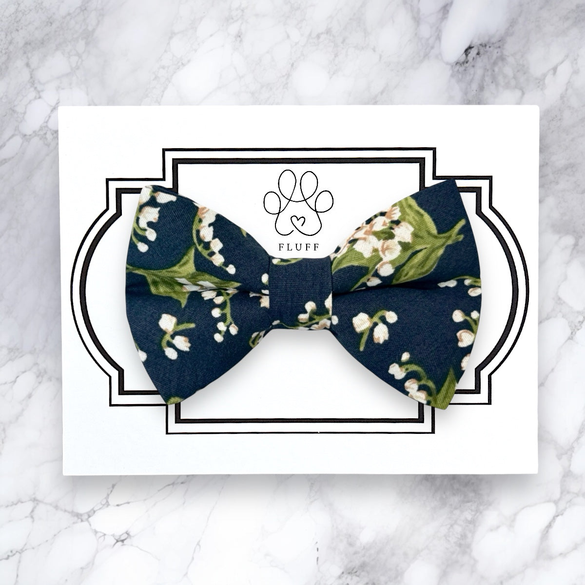 Navy blue bow tie with floral pattern on a white card with 'Fluff' brand logo.