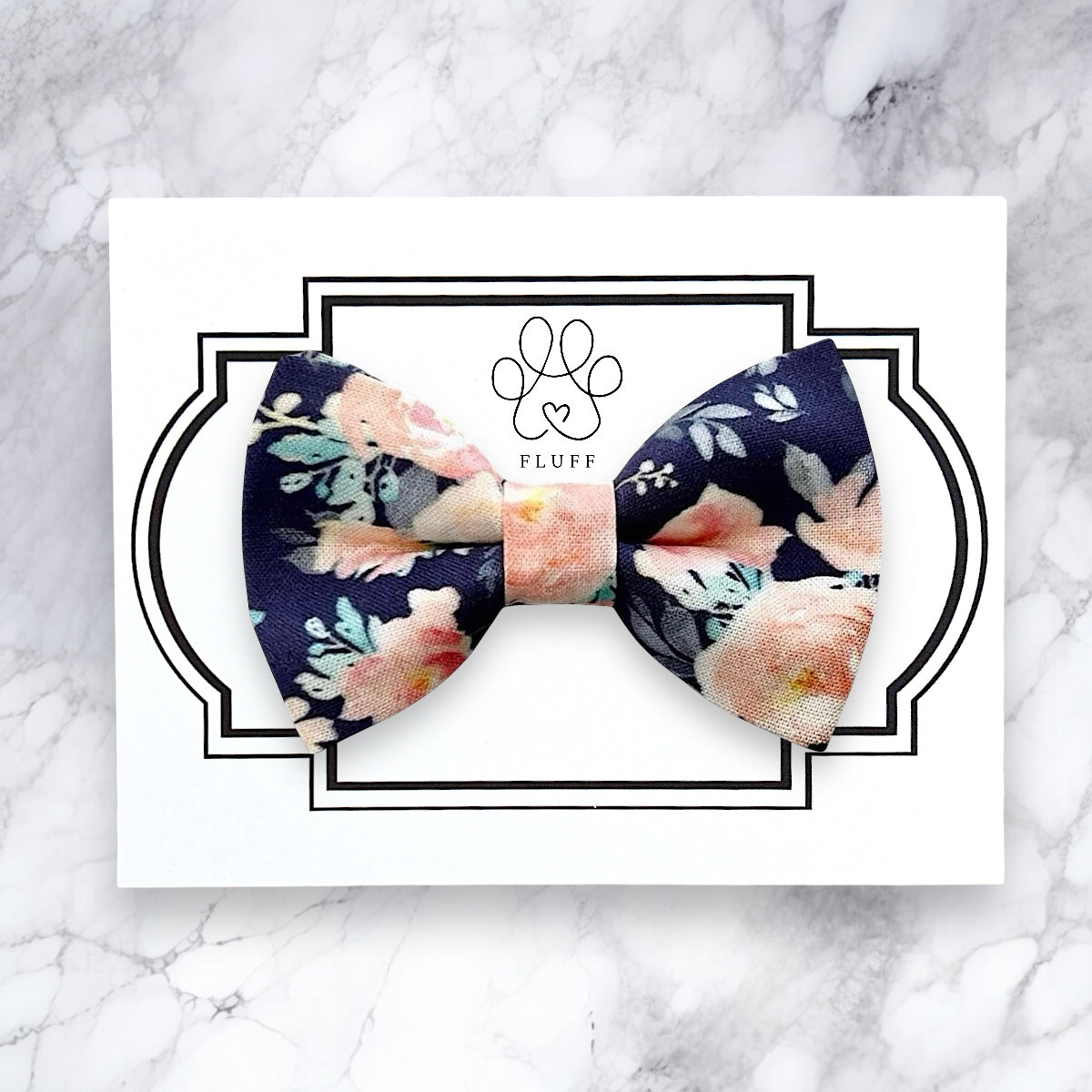 Floral dog bow tie with 'FLUFF' branding on a marble background