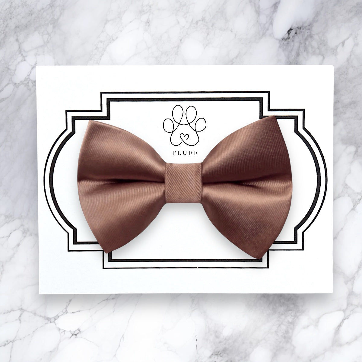 Brown bow tie on a white card with 'FLUFF' branding on a marble background