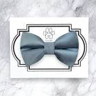 Dusty blue satin dog bow tie on a white card with 'FLUFF' branding on a marble background