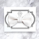 White dog bow tie on a card with 'FLUFF' branding on a marble background