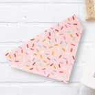 a pink napkin with sprinkles on it next to a cup of coffee